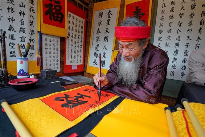 Cứ mỗi độ Xuân về, hình ảnh ông đồ già bày mực tàu giấy đỏ lại trở nên quen thuộc, mang theo những con chữ gửi gắm lời chúc phúc, may mắn và tài lộc. Ảnh: Khánh Hoà - TTXVN