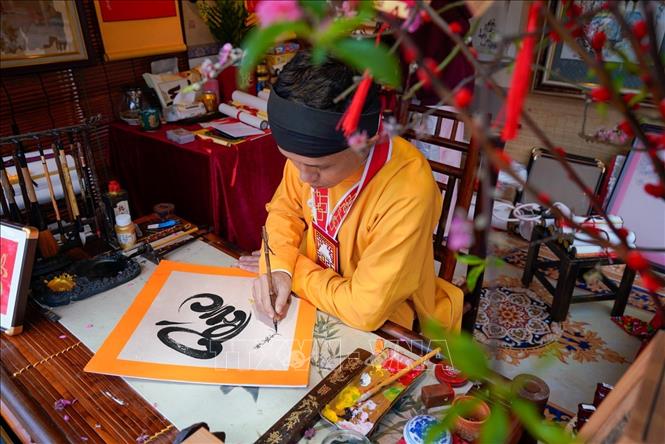 Cứ mỗi độ Xuân về, hình ảnh ông đồ bày mực tàu giấy đỏ lại trở nên quen thuộc, mang theo những con chữ gửi gắm lời chúc phúc, may mắn và tài lộc. Ảnh: Khánh Hoà - TTXVN