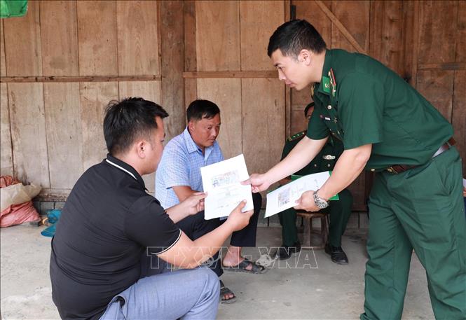 Cán bộ Đội vận động quần chúng Đồn Biên phòng Pa Tần phát tờ rơi tuyên truyền, phổ biến pháp luật phòng chống tội phạm. Ảnh: Quý Trung – TTXVN