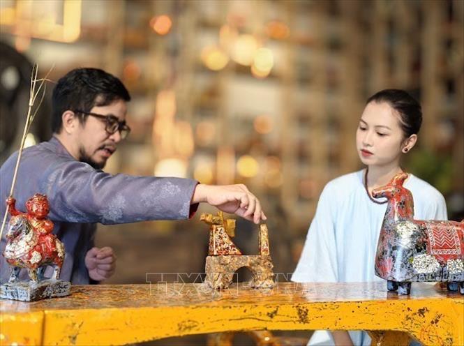 Nghệ nhân ưu tú Nguyễn Tấn Phát giới thiệu với khách hàng  về sụ kết hợp giữa nghệ thuật sơn mài và đá ong. Ảnh: Quốc Lũy - TTXVN