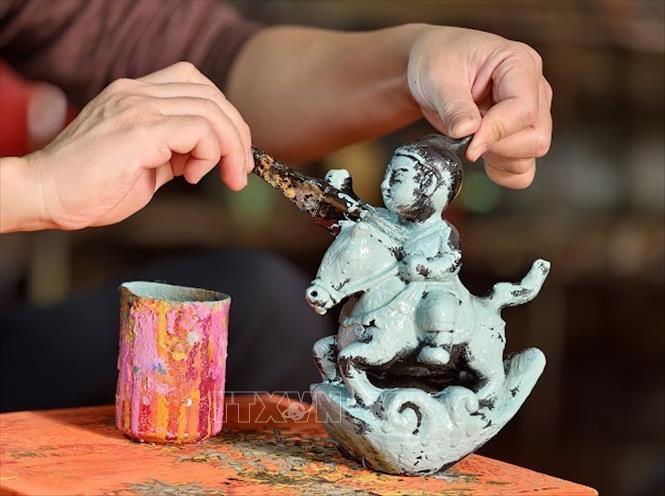 Nghệ nhân ưu tú Nguyễn Tấn Phát đang thực hiện công nghệ sơn sản phẩm ngựa. Ảnh: Quốc Lũy - TTXVN