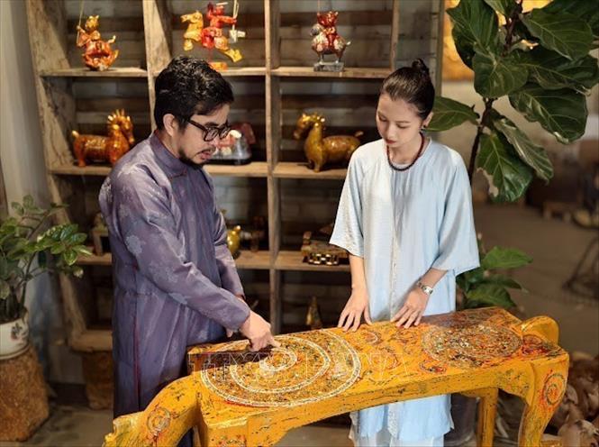 Nghệ nhân ưu tú Nguyễn Tấn Phát giới thiệu với khách hàng công nghệ sơn mài trên bộ sưu tập 