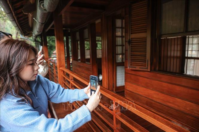 Người dân ghi lại kỷ niệm khi được thăm Nhà sàn Bác Hồ nằm trong khu di tích Chủ tịch Hồ Chí Minh. Ảnh: Hoàng Hiếu - TTXVN