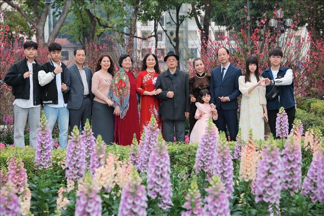 Một gia đình lưu giữ kỷ niệm tại Hồ Gươm khi các loài hoa đua hương, đua sắc đón Xuân. Ảnh: Hoàng Hiếu - TTXVN