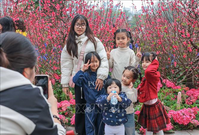 Một gia đình cho trẻ nhỏ đến du Xuân tại khu vực ven hồ Gươm. Ảnh: Hoàng Hiếu - TTXVN