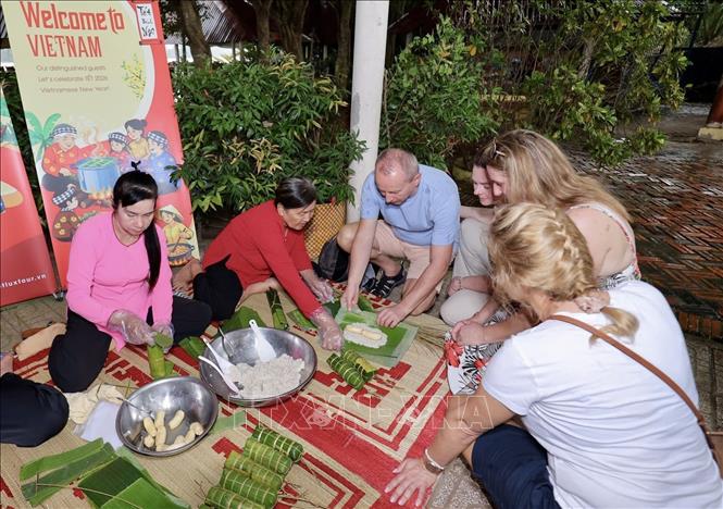 Khách nước ngoài trải nghiệm gói bánh Tét. Ảnh: Mỹ Phương – TTXVN