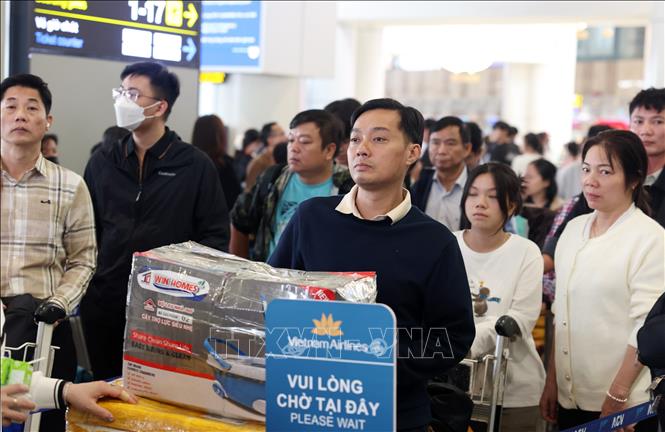 Hành khách xếp hàng chờ đến lượt vào khu vực làm thủ tục tại quầy của Vietnam Airlines, chiều mùng 5 Tết. Ảnh: Quốc Khánh - TTXVN