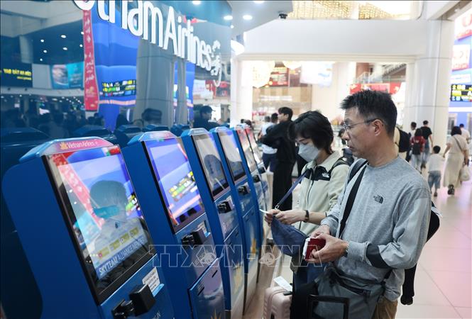 Một số người chọn cách làm thủ tục check-in tại quầy làm thủ tục tự động tại sân bay Nội Bài. Ảnh: Quốc Khánh - TTXVN