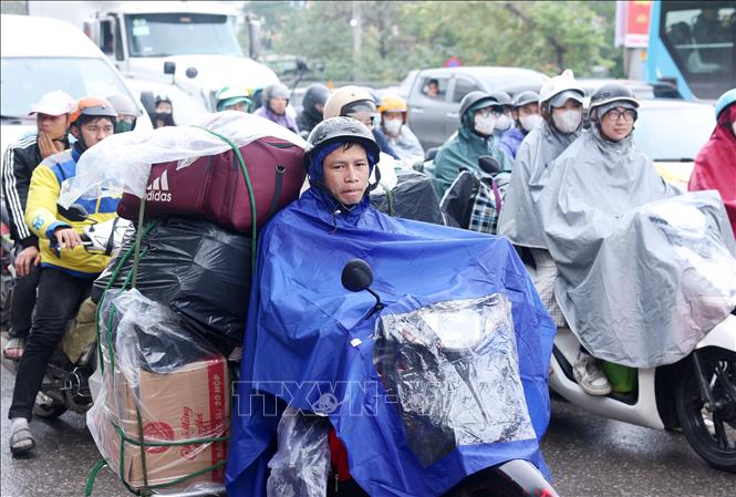 Người dân với đồ đạc lỉnh kỉnh quay trở lại Thủ đô sau kỳ nghỉ Tết trong mưa phùn và gió lạnh, chiều mùng 6 Tết. Ảnh: Quốc Khánh - TTXVN