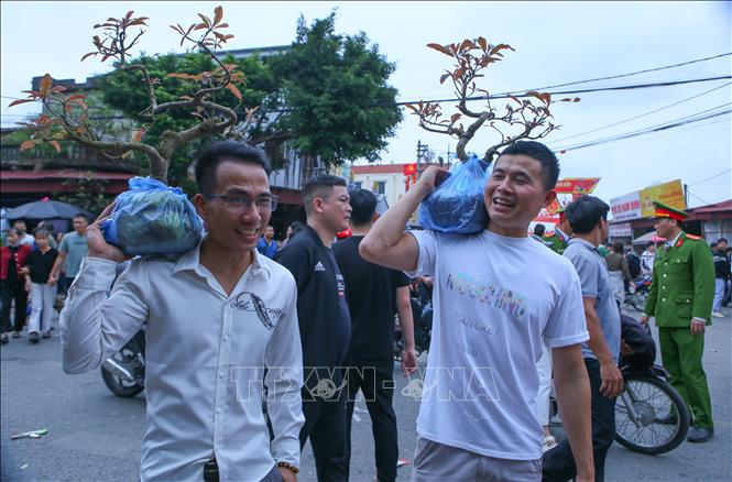 Niềm vui của khách khi chọn được món đồ ưng ý tại chợ Viềng nhân dịp đầu xuân năm mới.  Ảnh: Công Luật - TTXVN