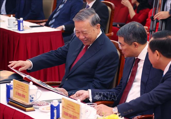 Tổng Bí thư Tô Lâm xem cuốn sách ảnh do phóng viên Ban biên tập Ảnh thực hiện. Ảnh: Văn Điệp - TTXVN