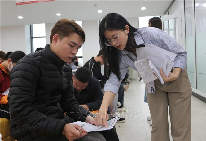 Nhân viên Công ty TNHH LG Display Việt Nam Hải Phòng hướng dẫn người tham gia tuyển dụng điền thông tin. Ảnh: Minh Thu - TTXVN