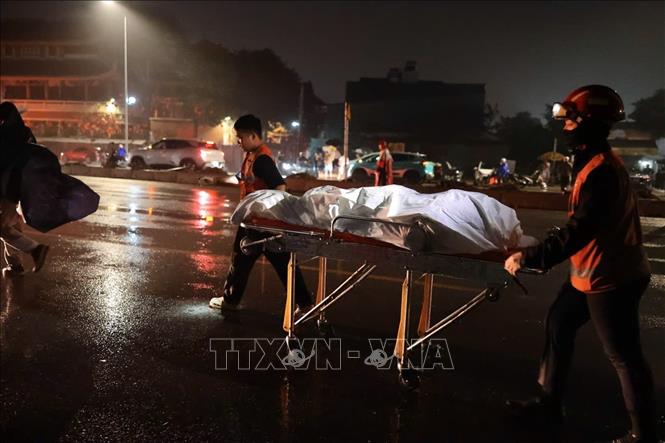 Lực lượng chức năng di chuyển nạn nhân khỏi hiện trường vụ tai nạn. Ảnh: Phạm Tuấn Anh - TTXVN
