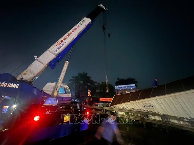 Lực lượng chức năng di chuyển ô tô tải bị nạn ra khỏi phạm vi đường sắt. Ảnh: Phạm Kiên - TTXVN