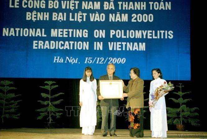 Phó Chủ tịch nước Nguyễn Thị Bình trao Huân chương Lao động hạng Nhất cho Chương trình tiêm chủng mở rộng quốc gia tại Lễ công bố Việt Nam đã thanh toán bệnh bại liệt vào năm 2000 (Hà Nội, 15/12/2000). Ảnh: Hữu Oai - TTXVN