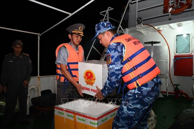 Đưa hòm phiếu vào thùng xốp để bảo quản khi Tổ bầu cử di chuyển từ tàu Kiểm ngư 260 sang tàu Cảnh sát biển 6008. Ảnh: TTXVN phát 