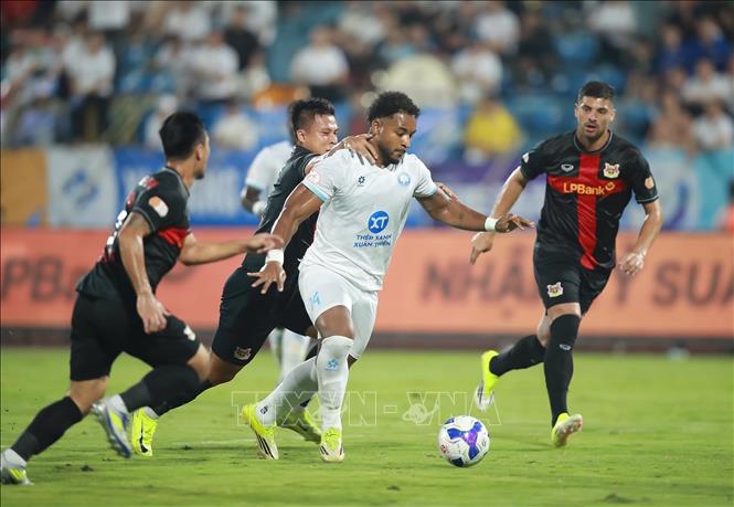 Cầu thủ Nguyễn Xuân Son (áo trắng, Thép Xanh Nam Định) dẫn bóng vượt qua các cầu thủ phòng ngự CLB Ninh Bình. Ảnh: Công Luật - TTXVN