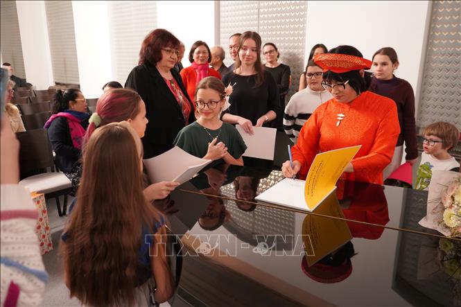 Nghệ sĩ Kiều Anh ký tặng các học sinh và phụ huynh tại buổi hòa nhạc. Ảnh: TTXVN            