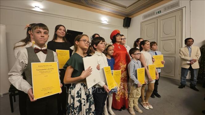 Các học sinh biểu diễn và nhận tập soạn nhạc cùng Nghệ sĩ Kiều Anh. Ảnh: TTXVN