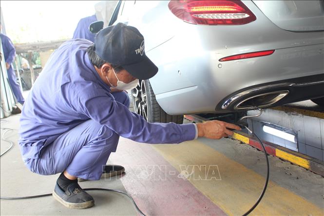 Nhân viên đăng kiểm thực hiện thao tác trong quy trình kiểm định khí thải. Ảnh: Nguyễn Thắng - TTXVN