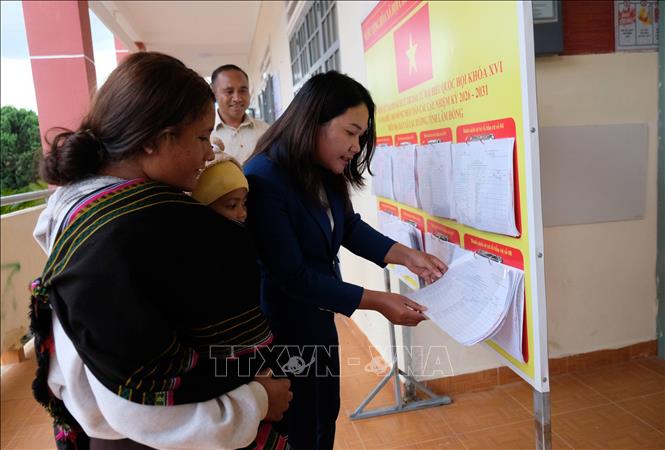 Chị Dà Ju K’Kim (thôn Long Lanh) được cán bộ xã Lạc Dương hỗ trợ kiểm tra thông tin của vợ chồng chị trong danh sách cử tri niêm yết tại UBND xã Lạc Dương. Ảnh: Nguyễn Dũng – TTXVN

