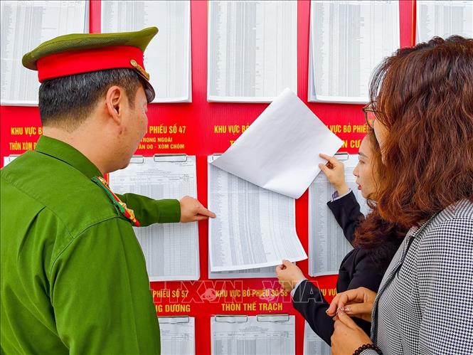 Cử tri xã Sóc Sơn tìm hiểu thông tin về các ứng cử viên được niêm yết công khai tại điểm bỏ phiếu. Ảnh: Trung Nguyên - TTXVN