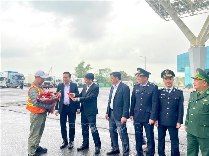 Lãnh đạo Ban Quản lý Khu kinh tế Cửa khẩu tặng hoa, lì xì đầu năm cho xe hàng xuất khẩu đầu tiên. Ảnh: TTXVN phát 