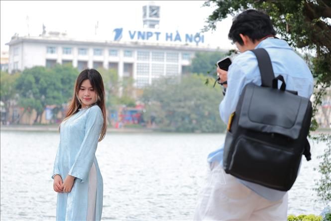Các bạn trẻ chụp ảnh cho nhau bên hồ Hoàn Kiếm, lưu giữ những khoảnh khắc đẹp của Hà Nội. Ảnh: Phạm Tuấn Anh - TTXVN