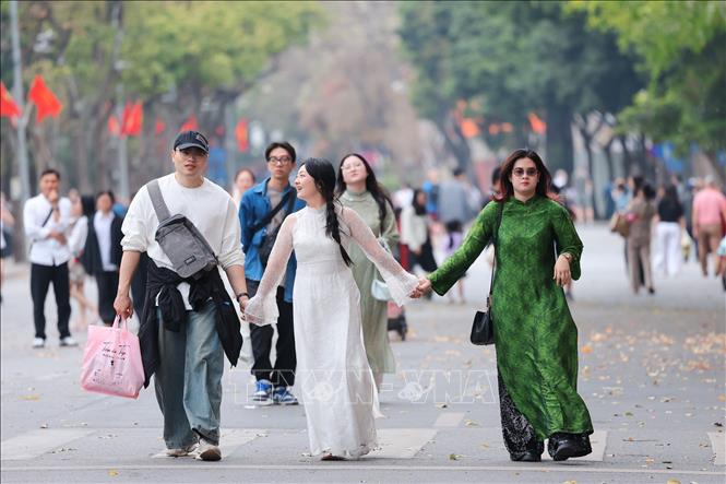 Các bạn trẻ tay trong tay vui đùa bên tà áo dài truyền thống. Ảnh: Phạm Tuấn Anh - TTXVN