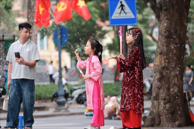 Trẻ em mặc áo dài vui chơi trên phố trung tâm Hà Nội. Ảnh: Phạm Tuấn Anh - TTXVN