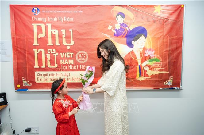 Bé gái tặng hoa cho mẹ nhân Ngày Quốc tế phụ nữ 8/3. Ảnh: Nguyễn Tuyến - PV TTXVN tại Nhật Bản