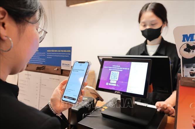 Người dân sử dụng mã QR để thanh toán tại cửa hàng đồ uống trên đường Phan Huy Chú (Hà Nội). Ảnh: Lê Đông - TTXVN