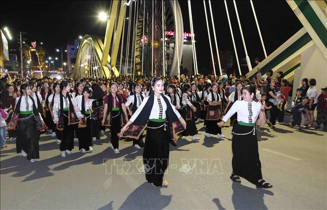 Đoàn phụ nữ trong trang phục dân tộc Thái diễu hành qua cầu Thanh Bình. Ảnh: Xuân Tư - TTXVN