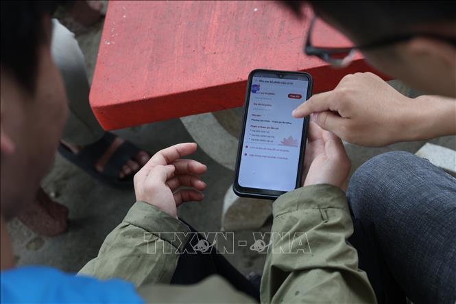 Sinh viên Trường Đại học Bách khoa, Đại học Đà Nẵng hướng dẫn nhau cách thay đổi nơi bỏ phiếu trên app VNeID. Ảnh: Xuân Quý - TTXVN