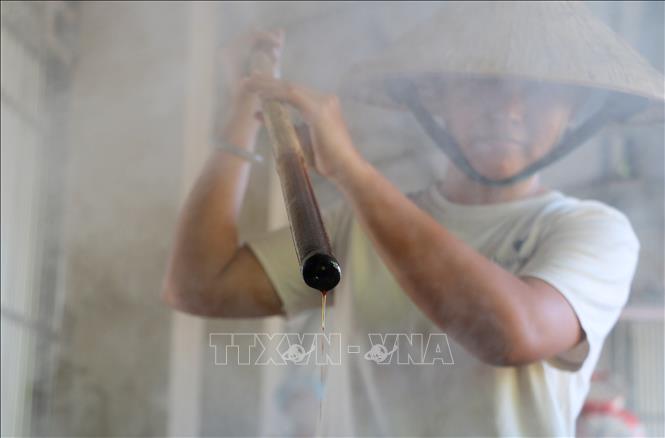 Sau thời gian nấu đạt yêu cầu, người thợ liên tục khuấy và kiểm tra, bao giờ đường thốt nốt trở thành dạng sệt, có màu vàng tươi đặc trưng thì nhắc chảo ra khỏi lò. Ảnh: Công Mạo-TTXVN