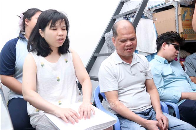 Chị Nguyễn Thị Cảnh, một cử tri khiếm thị 32 tuổi trú tại 194/4/9 đường Phạm Đình Túy, Bình Thạnh đọc tài liệu tiểu sử viết bằng chữ nổi về ứng cử viên đại biểu HĐND Thành phố nhiệm kỳ 2026-2031. Ảnh: Xuân Khu-TTXVN