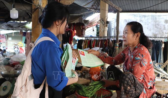 Đoàn viên, thanh niên xã Vĩnh Thuận Đông phát tờ rơi tuyên truyền về bầu cử tại chợ trung tâm xã. Ảnh: Hồng Thái - TTXVN