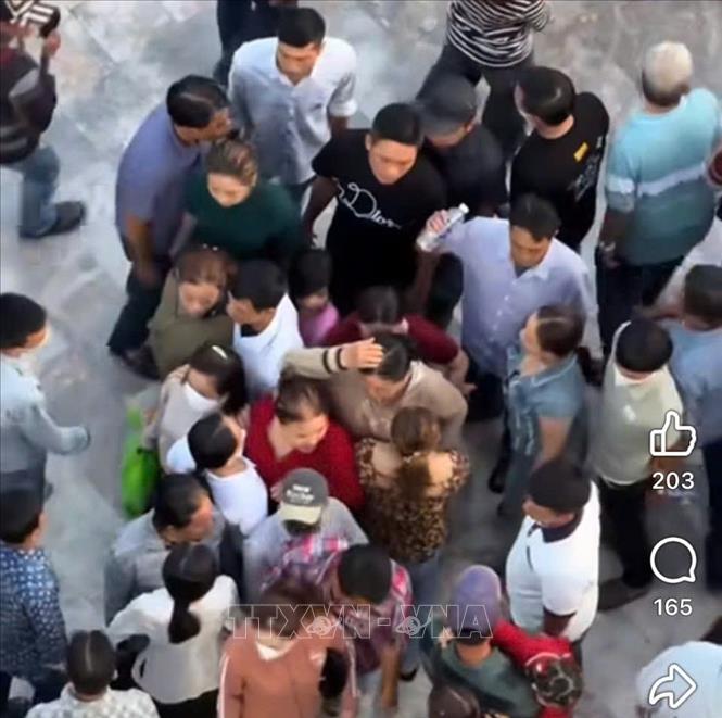 Hình ảnh đối tượng dàn cảnh giật dây chuyền của người phụ nữ (áo đỏ) tại khu vực tham quan Liên Hoa Bảo Tháp bị camera ghi lại. Ảnh: TTXVN phát