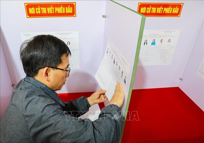 Thực hiện dán danh sách bầu cử tại cabin bầu cử. Ảnh: Khánh Hoà - TTXVN