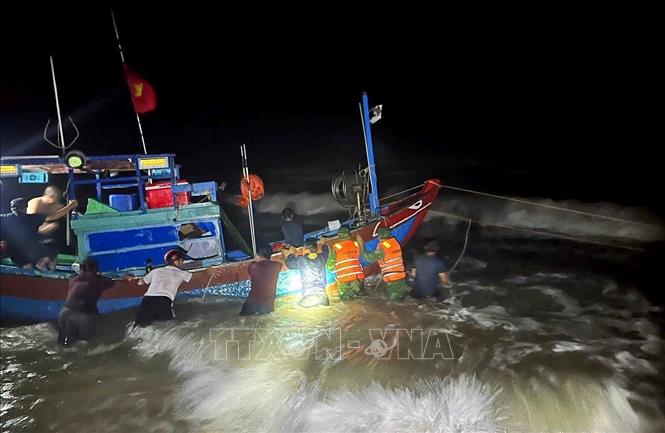 Lực lượng Biên phòng và người dân nỗ lực cứu nạn thuyền đánh cá bị mắc cạn đưa vào bờ an toàn. Ảnh: Võ Dung - TTXVN