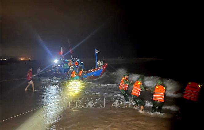 Đồn Biên phòng Lý Hòa, Bộ đội Biên phòng tỉnh Quảng Trị và người dân nỗ lực cứu nạn thuyền đánh cá bị mắc cạn đưa vào bờ an toàn. Ảnh: Võ Dung - TTXVN