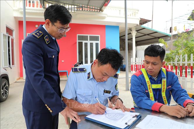 Cán bộ Đội Quản lý thị trường số 6, Chi cục QLTT  tuyên truyền, yêu cầu các cửa hàng xăng dầu ký cam kết không găm hàng, đầu cơ, tăng giá trái quy định trong bối cảnh giá xăng biến động. Ảnh: Khiếu Tư - TTXVN