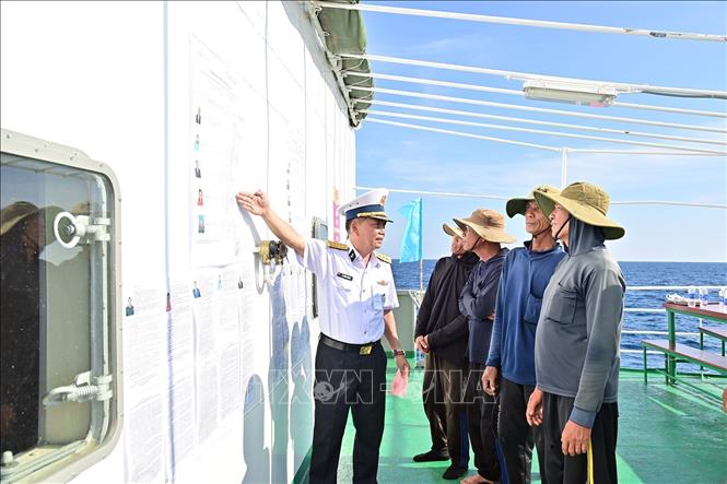 Đại tá Lê Hồng Quang, Phó Chủ nhiệm Chính trị Vùng 2 Hải quân, Tổ trưởng Tổ bầu cử sớm trên biển hướng dẫn cho ngư dân tàu cá QNg 96435 TS nắm thể lệ bầu cử. Ảnh: TTXVN phát 