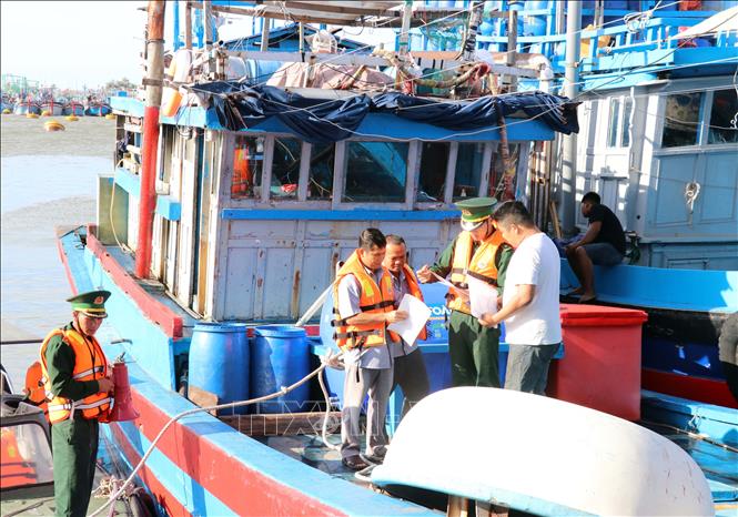 Lực lượng Trạm kiểm soát Biên phòng Cà Ná và Ban quản lý Cảng cá Cà Ná kiểm tra giấy tờ liên quan đến tàu thuyền của ngư dân. Ảnh: Công Thử - TTXVN