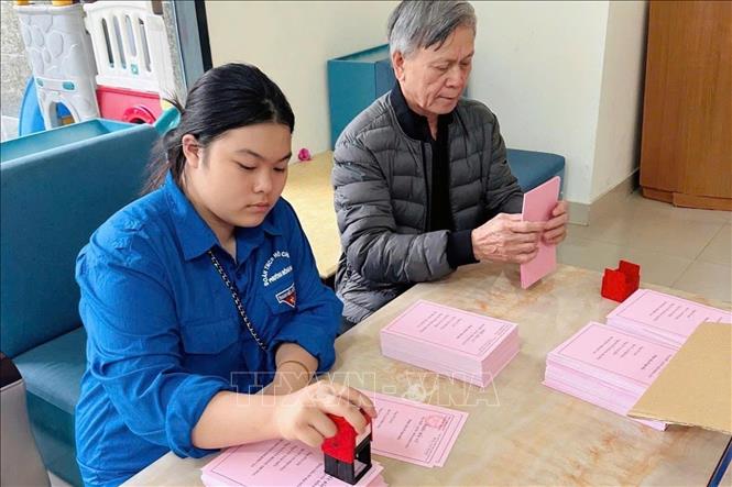 Các tình nguyện viên giúp tổ bầu cử đóng dấu, ghép tập phiếu bầu. Ảnh: Minh Ánh/TTXVN phát