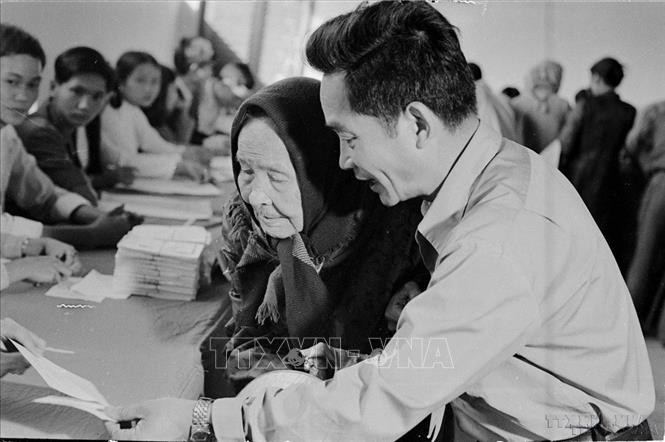 Để thể hiện tính liên tục của Nhà nước qua các giai đoạn đấu tranh cách mạng, Quốc hội đã quy định khóa Quốc hội của nước Việt Nam thống nhất là Quốc hội khóa VI. Trong ảnh: Mặc dù già yếu, Cụ Lê Thị Dưỡng (86 tuổi, đường Lý Thường Kiệt, TP.Huế), vẫn nhờ người cõng đến hòm phiếu tham gia bầu cử Quốc hội khóa VI (25/4/1976). Ảnh: Sỹ Thái - TTXVN