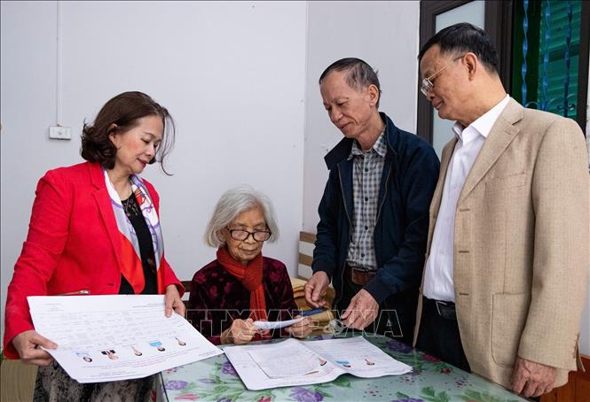 Cán bộ phường Hồng Hà đến tận nhà giới thiệu danh sách người ứng cử và tài liệu phục vụ bầu cử cho cử tri Vũ Thị Tuyết (95 tuổi), đảng viên 75 năm tuổi Đảng. Ảnh: Vân Chi/TTXVN phát

