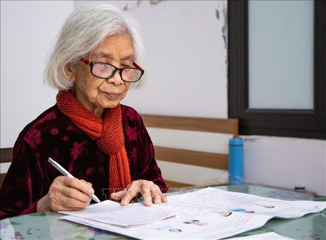Bà Vũ Thị Tuyết, (95 tuổi), đảng viên 75 năm tuổi Đảng nghiên cứu, ghi chép thông tin các ứng cử viên, với tiêu chí lựa chọn những người có đủ trình độ, năng lực và đạo đức. Ảnh: Vân Chi/TTXVN phát
