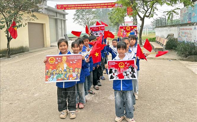 Học sinh xã Hiệp Hòa (tỉnh Bắc Ninh) cầm cờ Tổ quốc và pano tuyên truyền, tham gia hoạt động cổ động hướng tới ngày bầu cử. Ảnh: Đồng Thúy-TTXVN