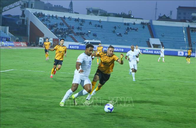 Tình huống tranh chấp bóng giữa cầu thủ Thép Xanh Nam Định (áo trắng) và cầu thủ Đông Á Thanh Hóa. Ảnh: Công Luật - TTXVN